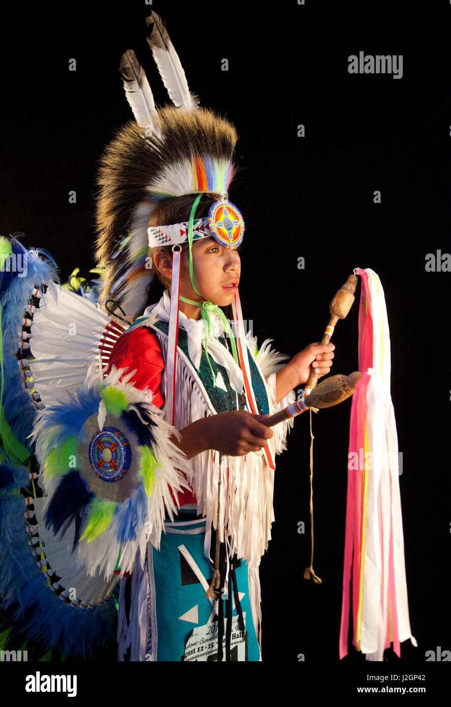 Plaqués agitation dancer Pacer Allan Tobey (Assiniboine, Sioux) habillés en costumes de pow-wow à plumes colorées grouille, tablier et coiffe roach tient deux bâtons de danse avec des rubans. Banque D'Images