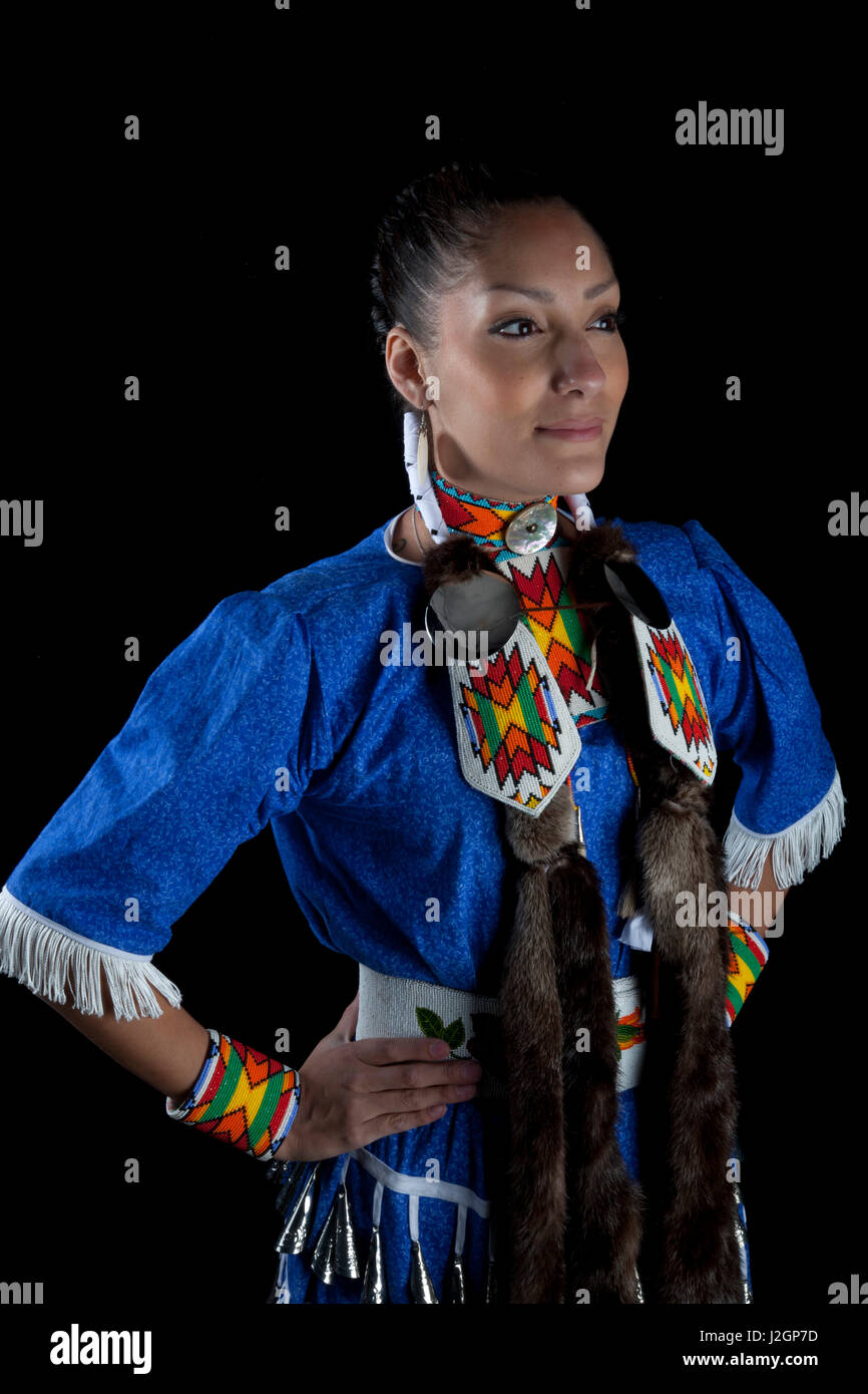 Adolescente traditionnel, Challis Baldwin (Shoshone-Bannock), habillé en robe de danseuse jingle pow wow et pose de perles sur un fond noir. Banque D'Images