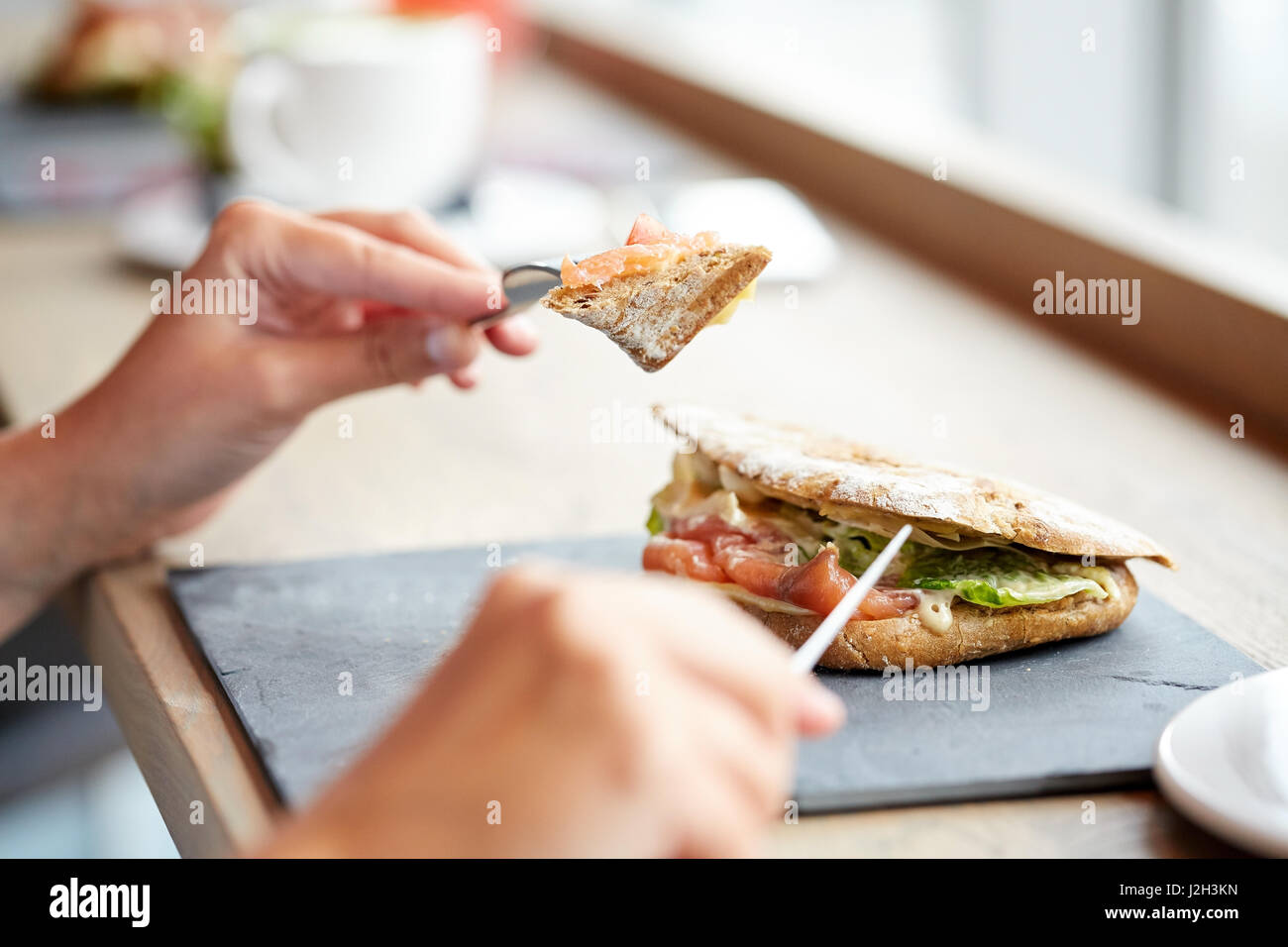 Woman eating sandwich panini au saumon au restaurant Banque D'Images
