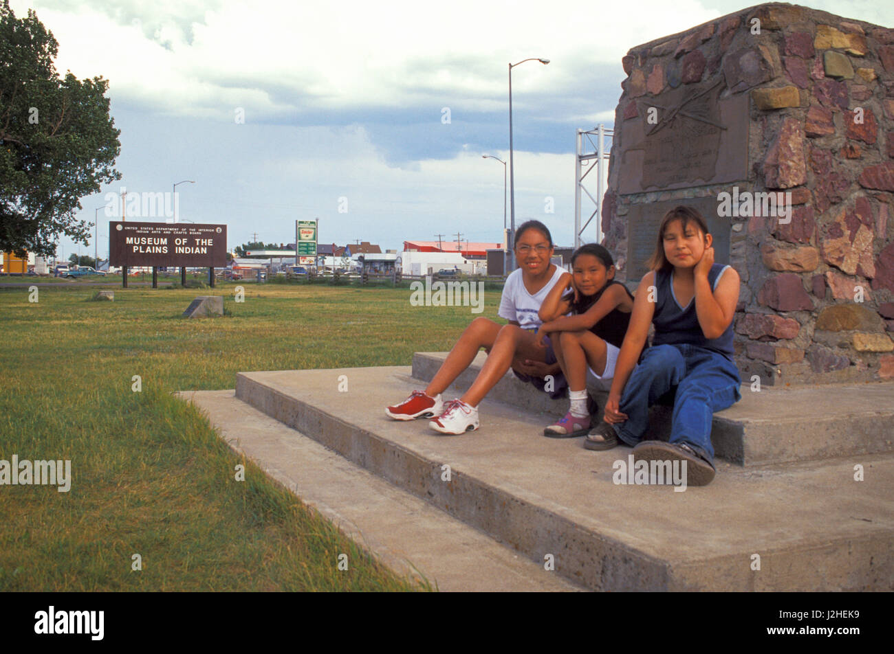 Trois enfants Blackfeet siéger ensemble au rock monument mémorial situé devant le musée des Indiens des plaines du Montana à Browning Banque D'Images