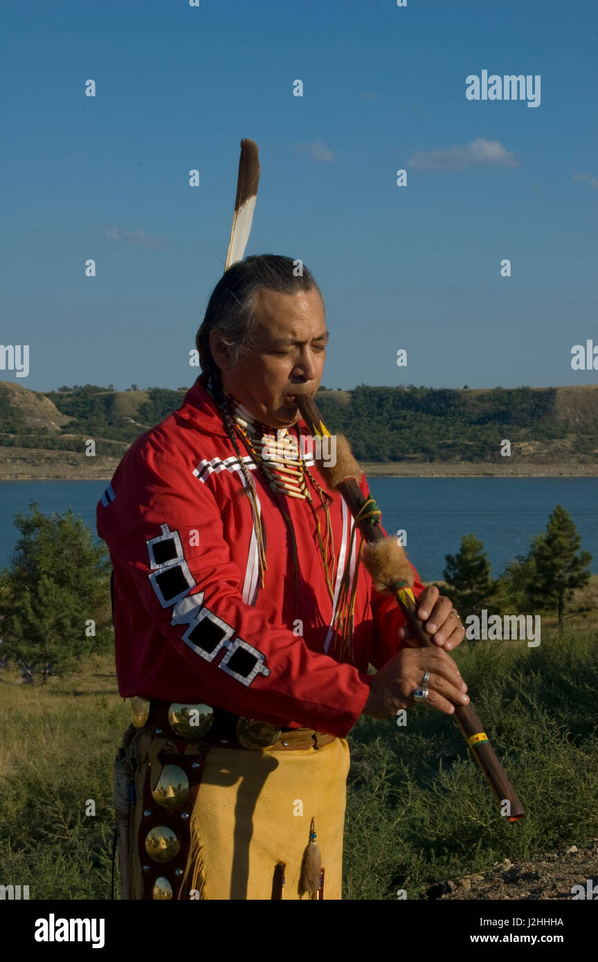 Habillé en costume traditionnel de jambières en peau de daim, breechcloth et ruban rouge shirt est native flute player Keith Bear (Mandans) avec la rivière Missouri, dans l'arrière-plan sur la réserve indienne de Fort Berthold des Trois tribus affiliées, ND Banque D'Images