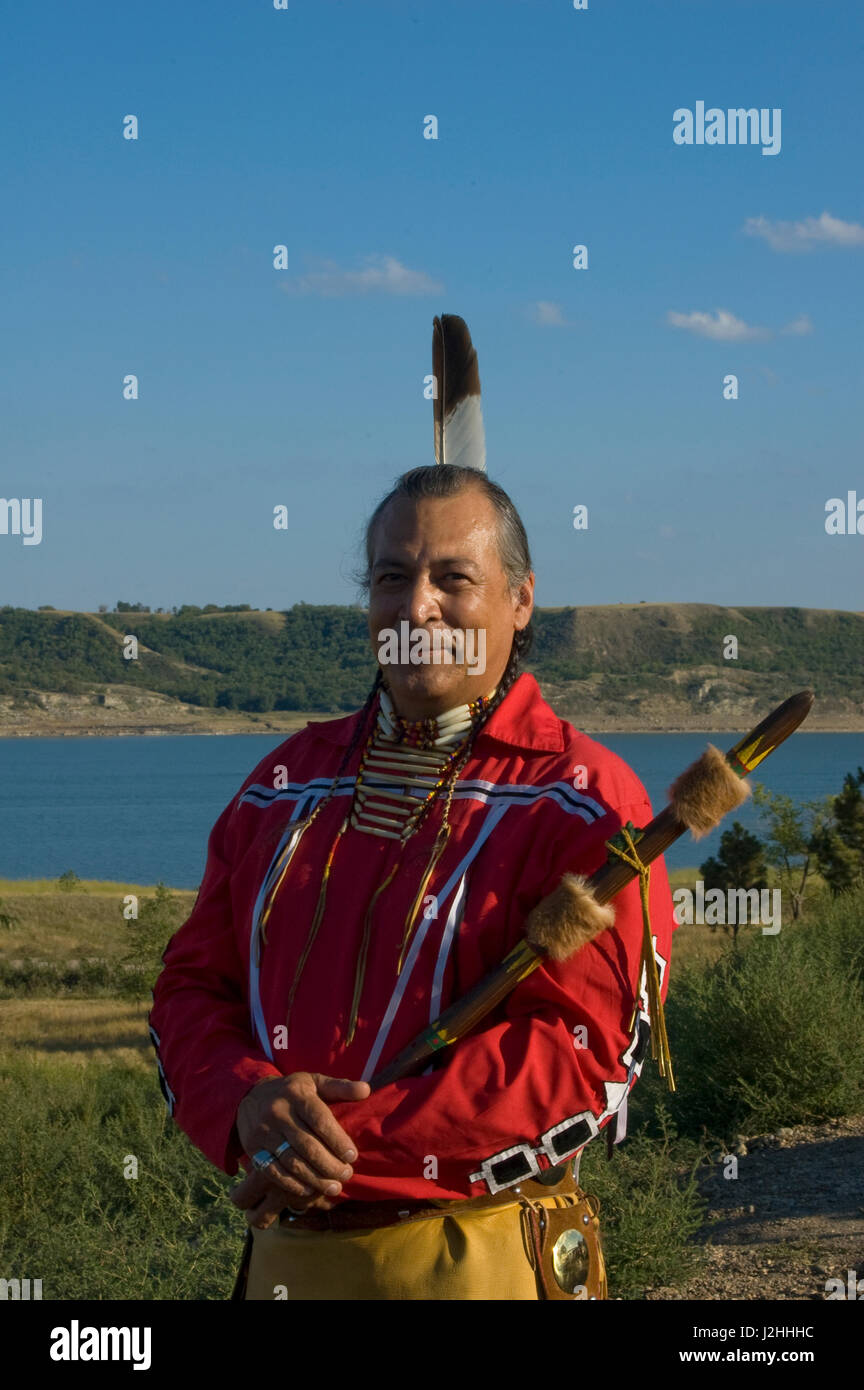 Habillé en costume traditionnel de jambières en peau de daim, breechcloth et ruban rouge shirt est native flute player Keith Bear (Mandans) avec la rivière Missouri, dans l'arrière-plan sur la réserve indienne de Fort Berthold des Trois tribus affiliées, ND Banque D'Images