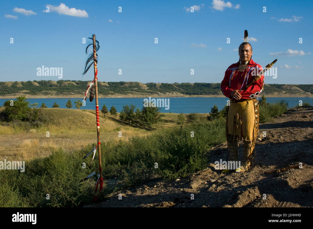 Trois tribus affiliées membre d'une tribu, Keith Ours, est un joueur de flûte traditionnelle autochtone qui est debout à côté d'un personnel de l'Aigle orné de fourrure queue buffalo surplombant le lac Sakakawea dans l'arrière-plan Banque D'Images