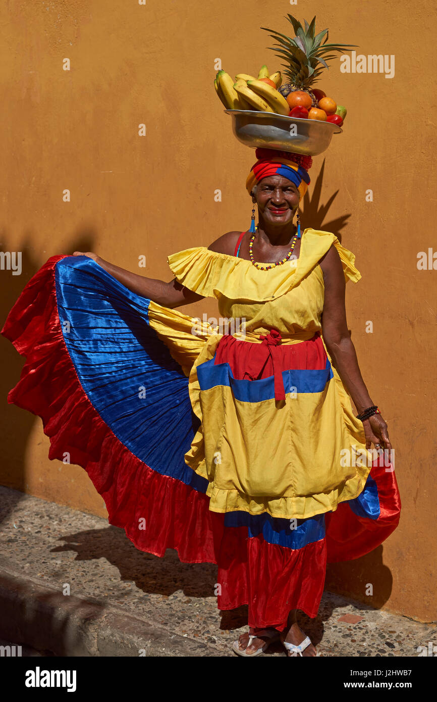 Femme en costume traditionnel qui pose pour une photographie tout en vendant des fruits dans l'historique ville fortifiée de Cartagena de Indias en Colombie. Banque D'Images