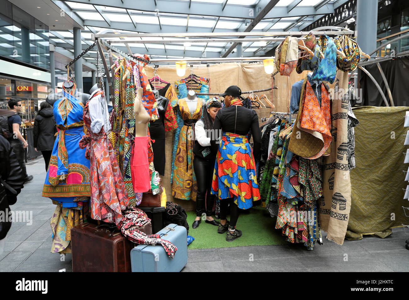 Une belle grande femme essaie sur une robe d'impression de l'Afrique dans le marché de Spitalfields, Londres UK KATHY DEWITT Banque D'Images