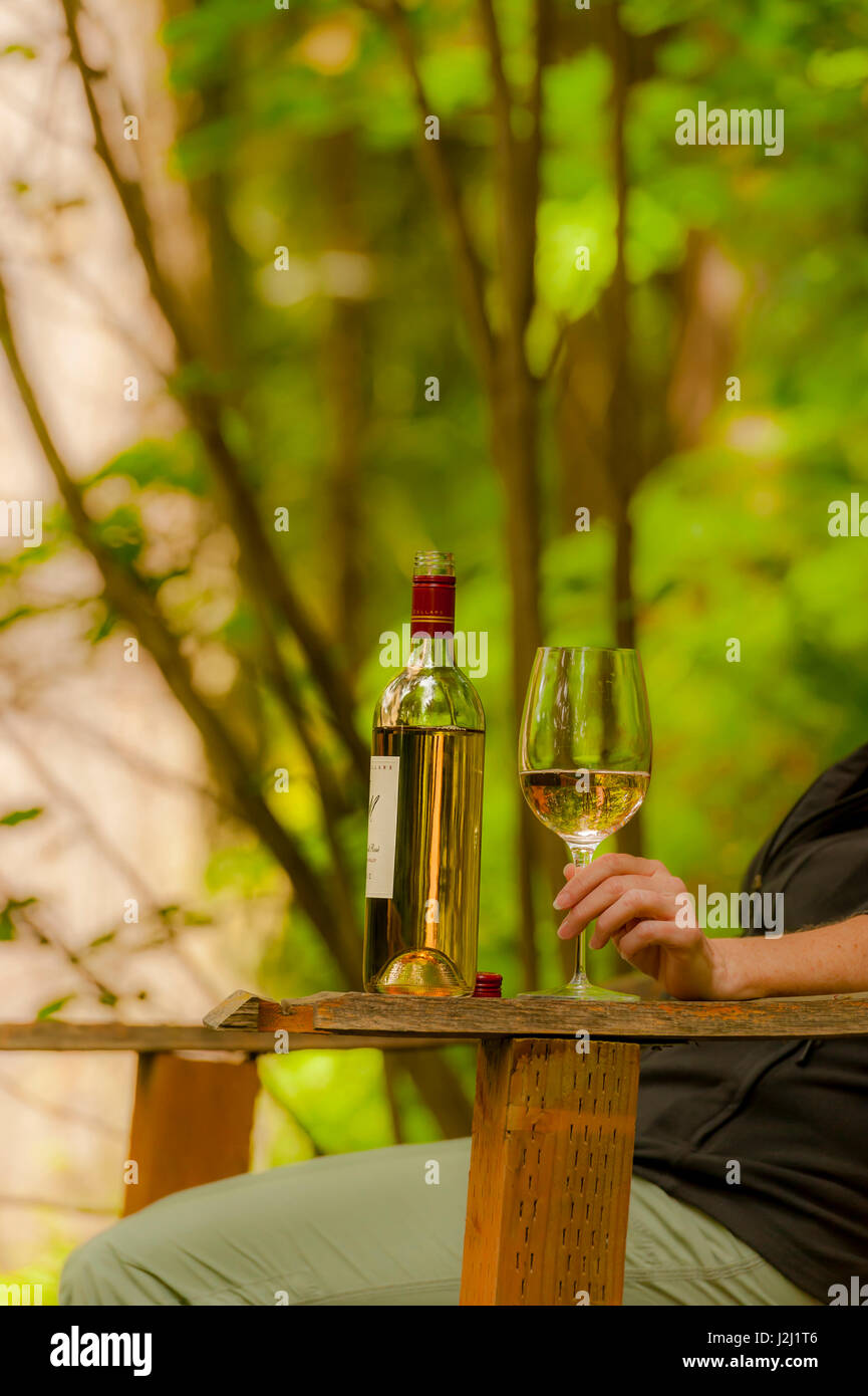 L'État de Washington, USA, Florida. Femme assise avec du vin blanc pour une dégustation en plein air chez JM Cellars. Banque D'Images