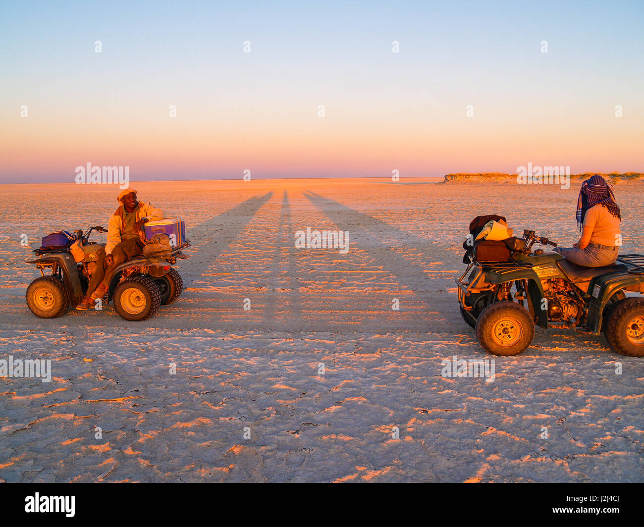 Guide touristique et en éclat de soleil couchant en quad arrêter pendant la traversée de Makgadikgadi Pans National Park, vaste région pittoresque de sel désert pan Banque D'Images