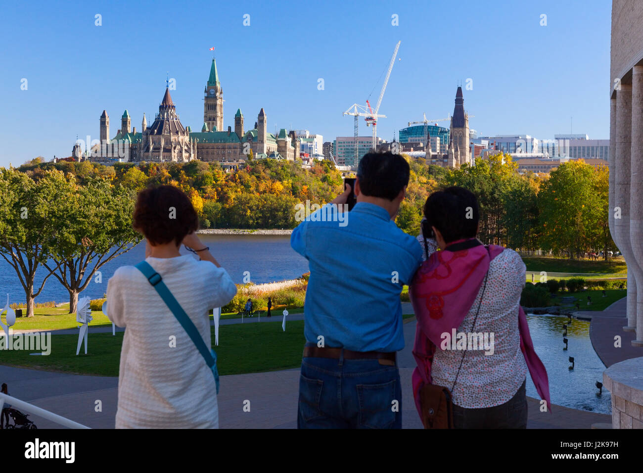 La colline du Parlement à Ottawa, en Ontario, avec au premier plan les touristes prendre des photos vu de Hull, Gatineau, Québec, Canada. Banque D'Images