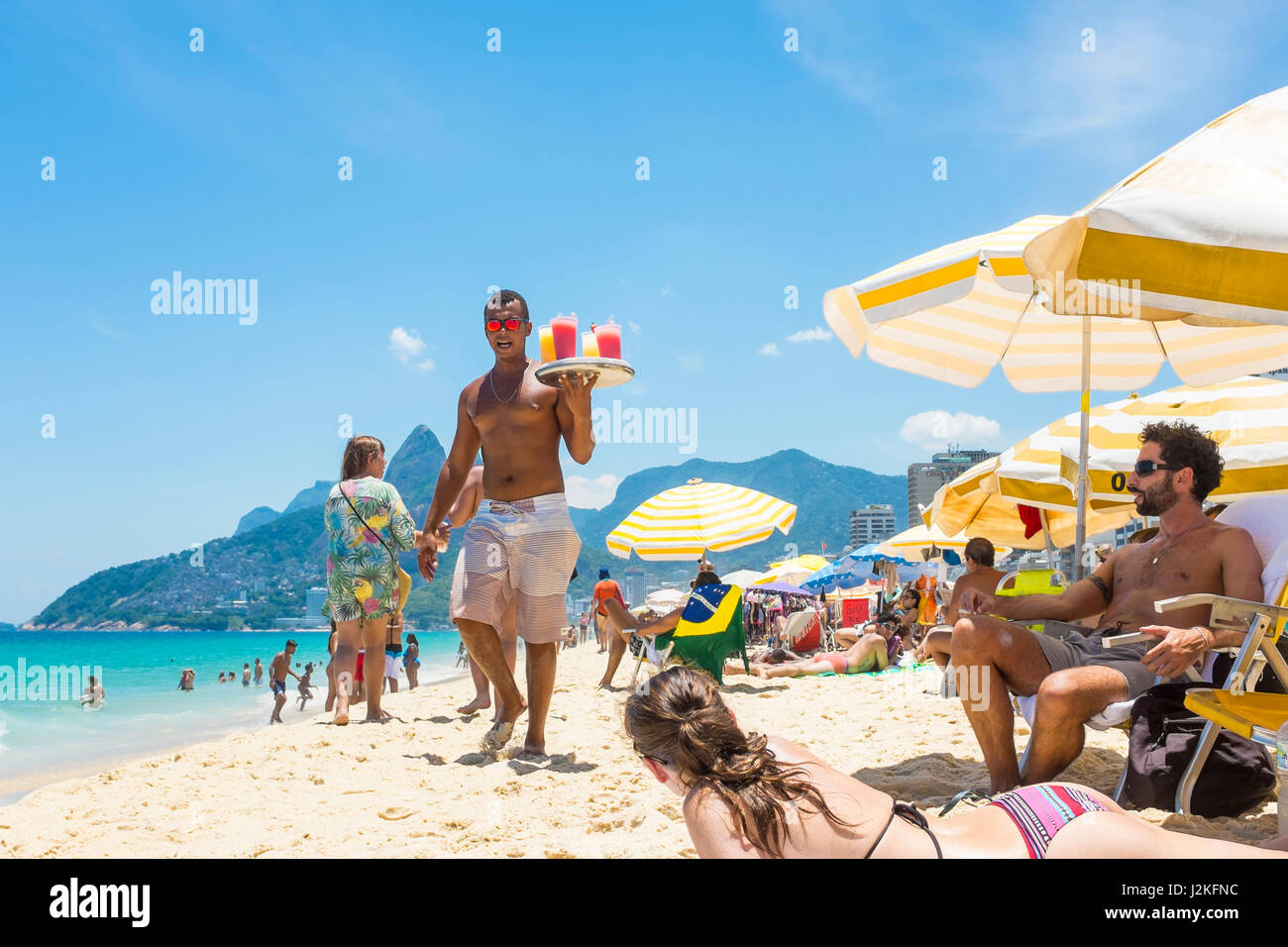 RIO DE JANEIRO - le 24 janvier 2017 : jeune Brésilien vendeur porte un plateau de caipirinha cocktails dans le soleil de midi sur la plage d'Ipanema. Banque D'Images