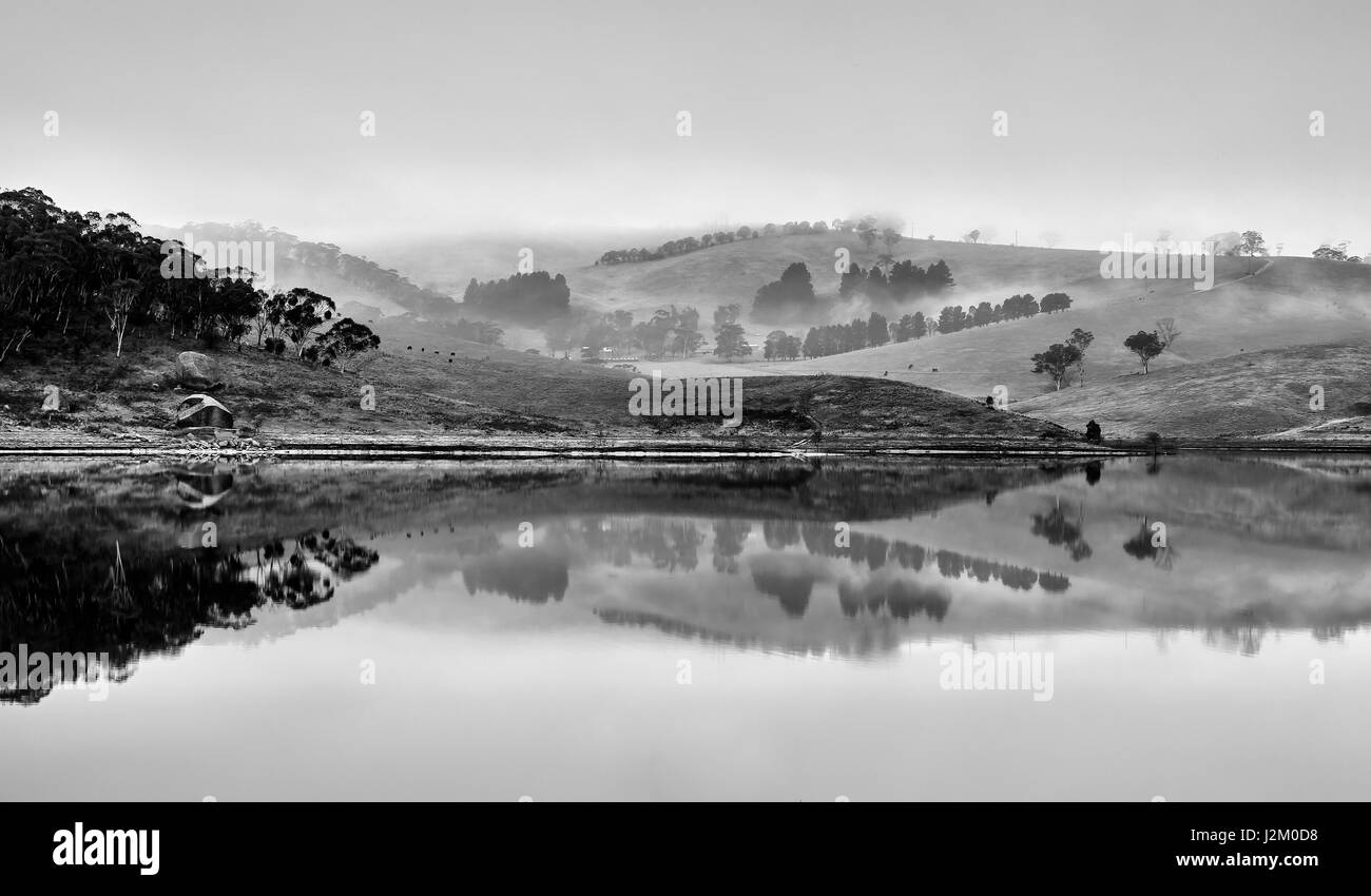 Noir blanc large panorama de collines et ferme de pâturage autour du lac sur la rivière Coxs Lyell dans les Montagnes Bleues de l'Australie. Matin brumeux whi paysage couvre Banque D'Images