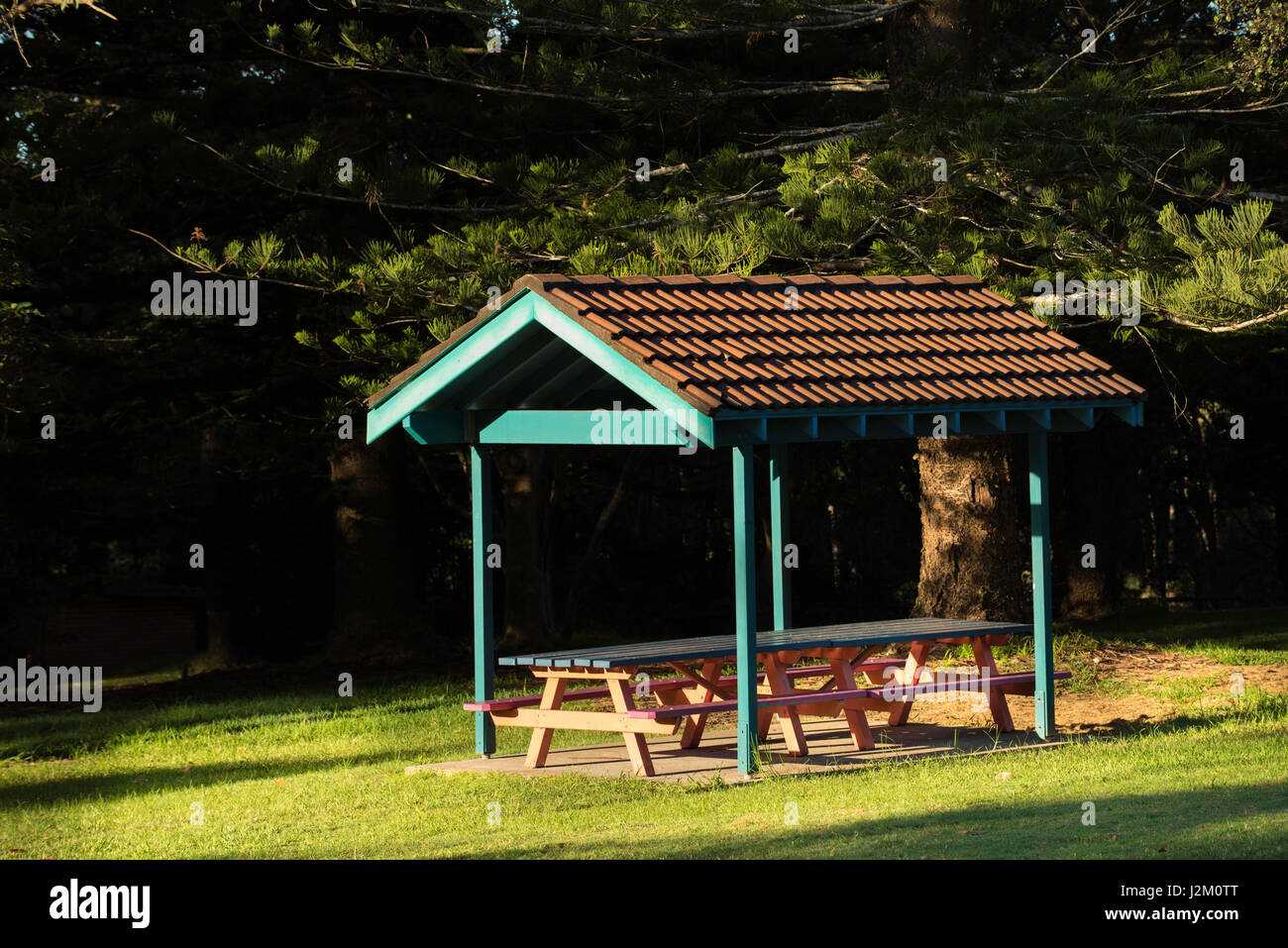 Un toit en terre cuite au-dessus d'une table de pique-nique et de chaises dans un parc à Black Head Beach en Nouvelle-Galles du Sud, en Australie Banque D'Images