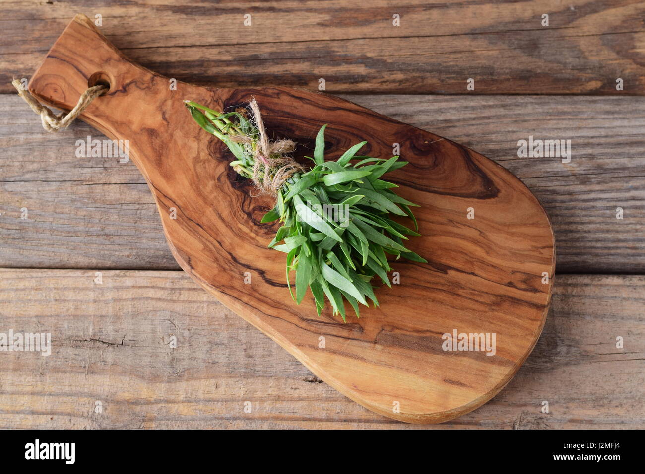 Un bouquet d'estragon frais sur une planche à découper en bois. Banque D'Images