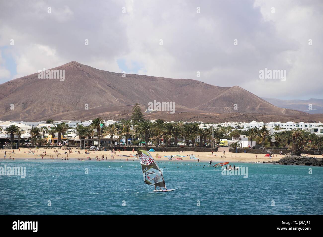 Les personnes qui apprennent à wind surf avec plage et le volcan en arrière-plan à Costa Teguise, Lanzarote, Îles Canaries Banque D'Images