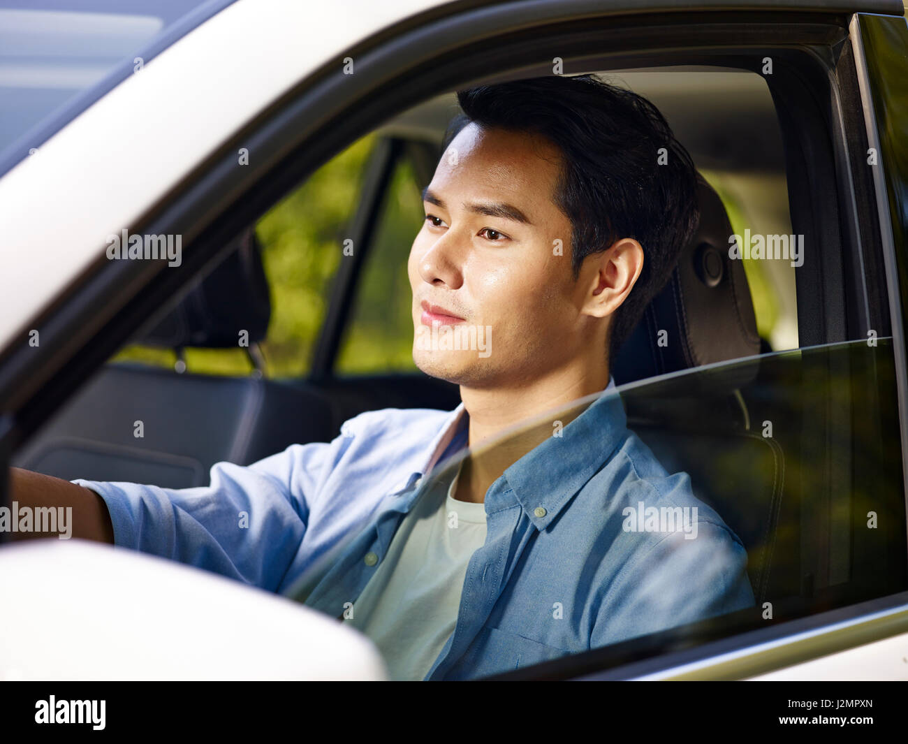 Young Asian man driving a car, heureux et souriant. Banque D'Images
