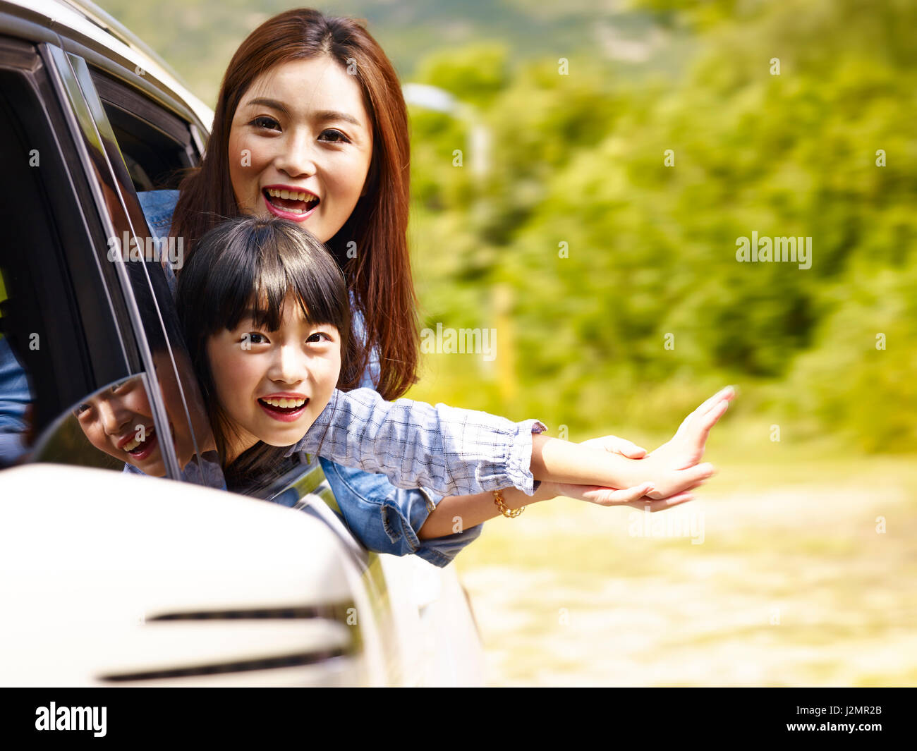Happy asian mother and daughter having fun tout en montant en voiture familiale. Banque D'Images