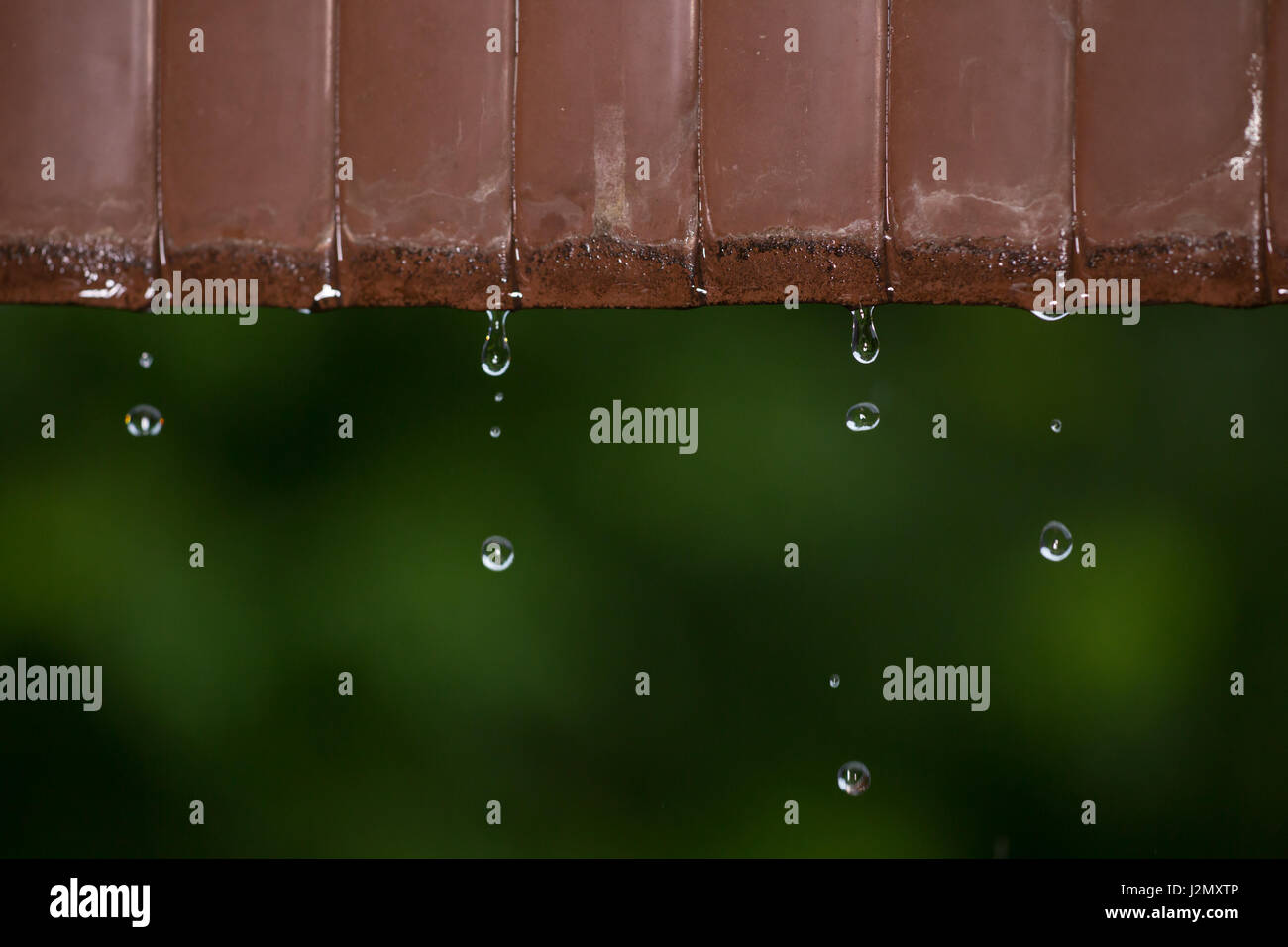 L'eau de pluie passant de vieux métal rouillé toiture d'un jour froid, vitesse d'obturation lente pour montrer le mouvement de l'eau et sélective l'accent sur une goutte d'eau Banque D'Images