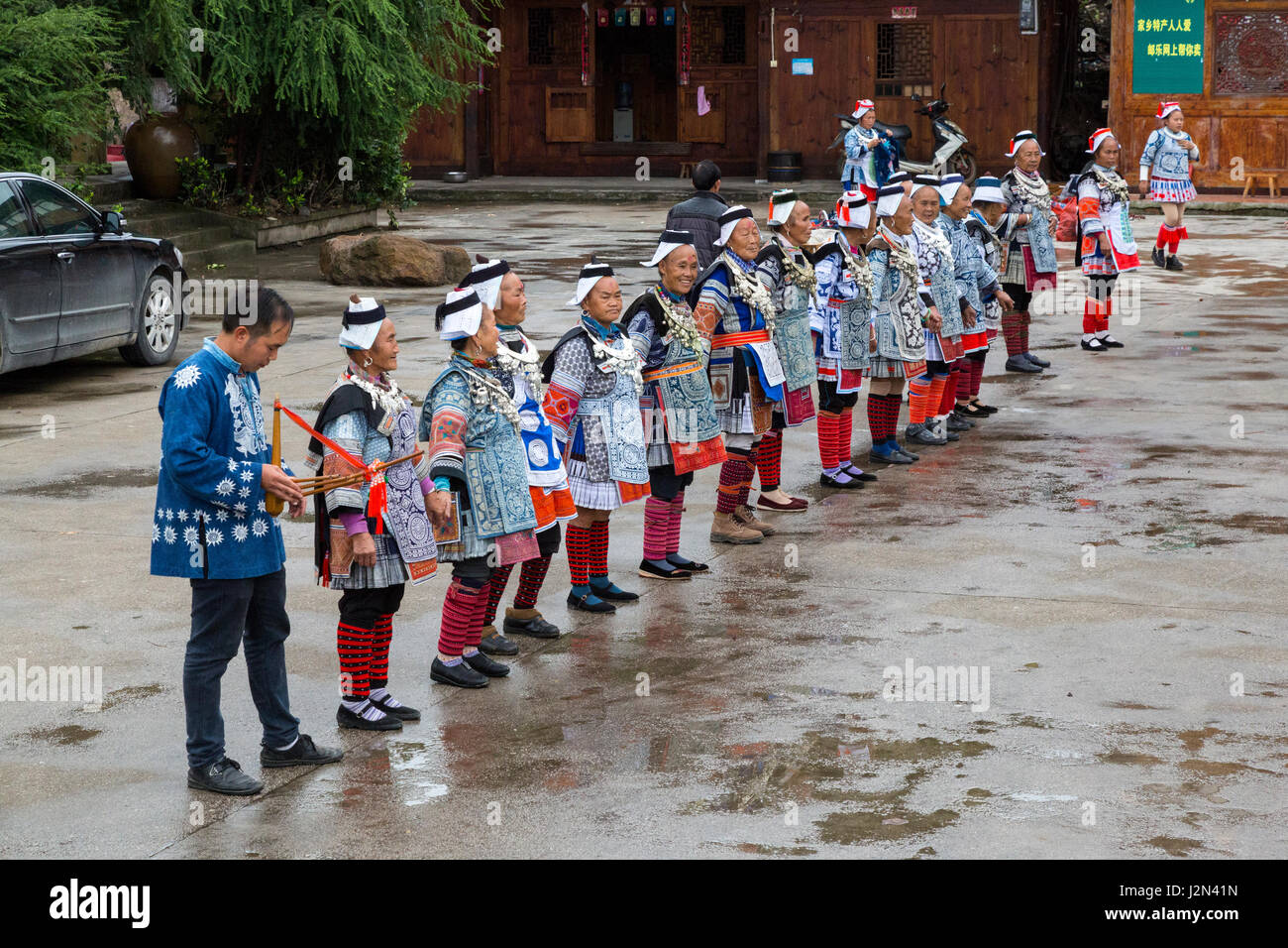 Matang, Village Gejia du Guizhou, en Chine. Les femmes et joueur de flûte Accueillir les visiteurs dans le village. Banque D'Images