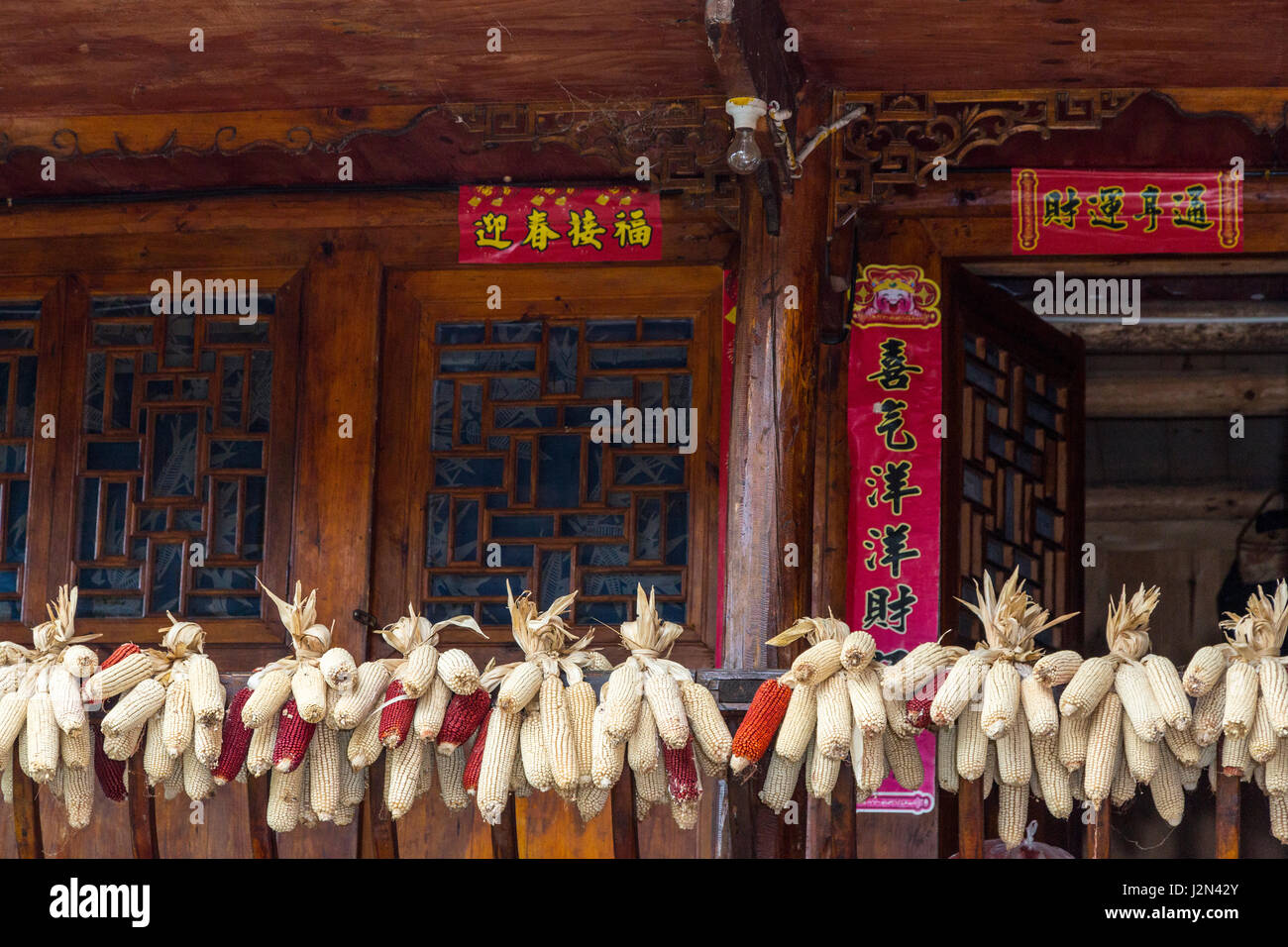 Matang, Village Gejia du Guizhou, en Chine. Épis de maïs accroché sur main courante à l'entrée de la Chambre. Fête du printemps (Nouvel An) morte autour de la porte. Banque D'Images