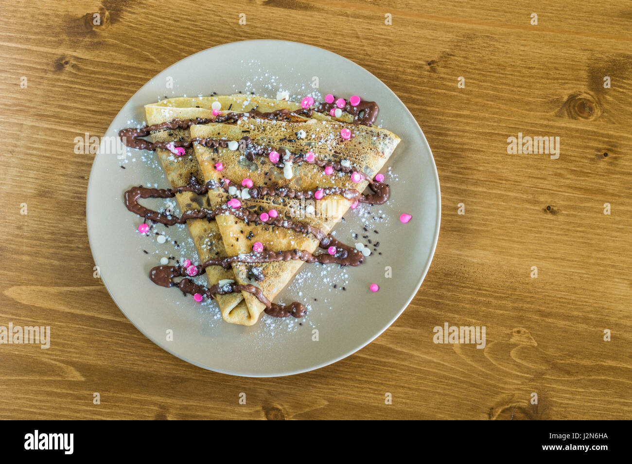 Vue de dessus avec crêpe délicieuse crème au chocolat et chocolat et pure servi sur assiette blanche sur une table en bois Banque D'Images