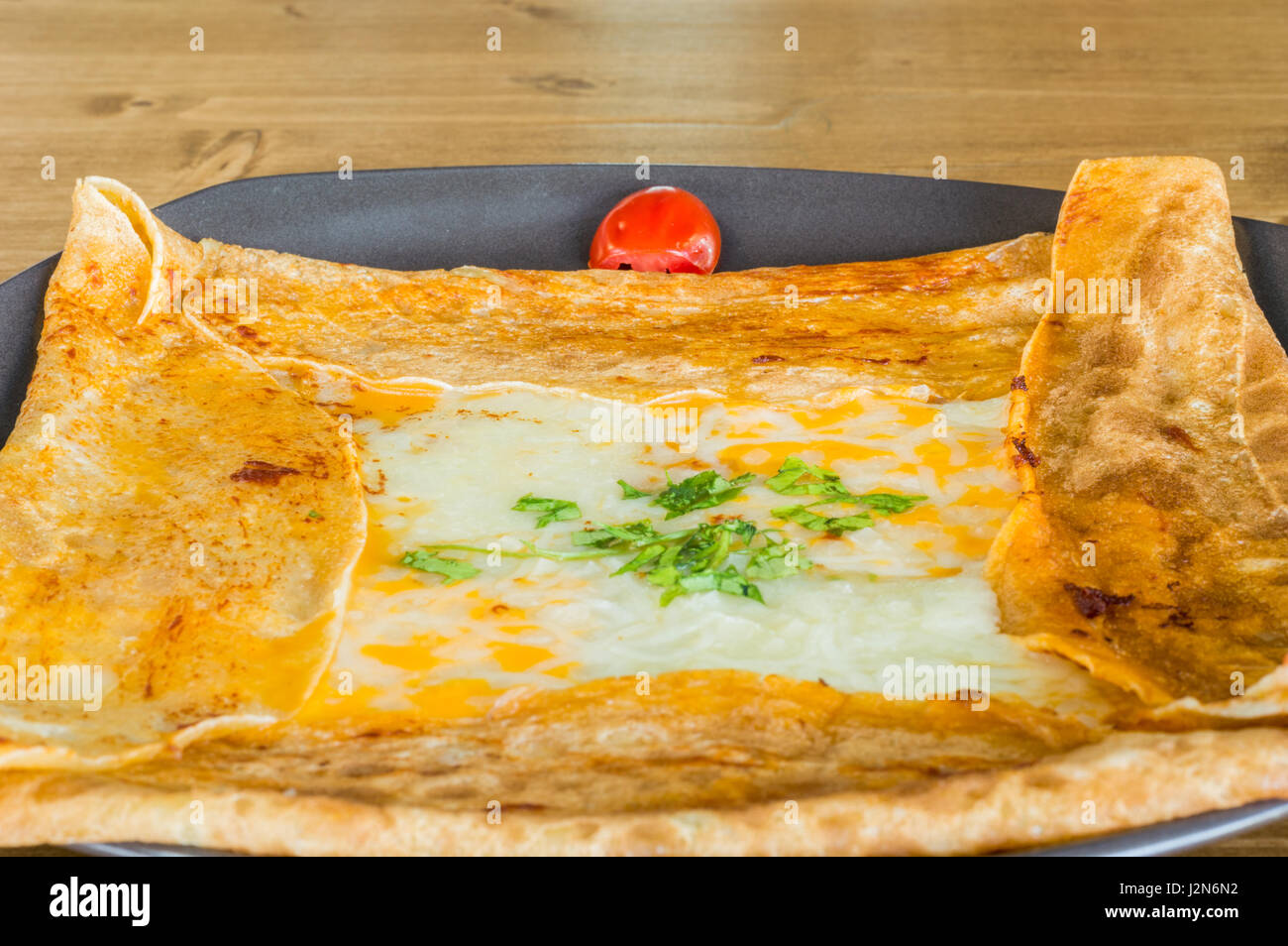 Gros plan du délicieux fromage cheddar avec crêpe servie sur une plaque gris sur une table en bois Banque D'Images