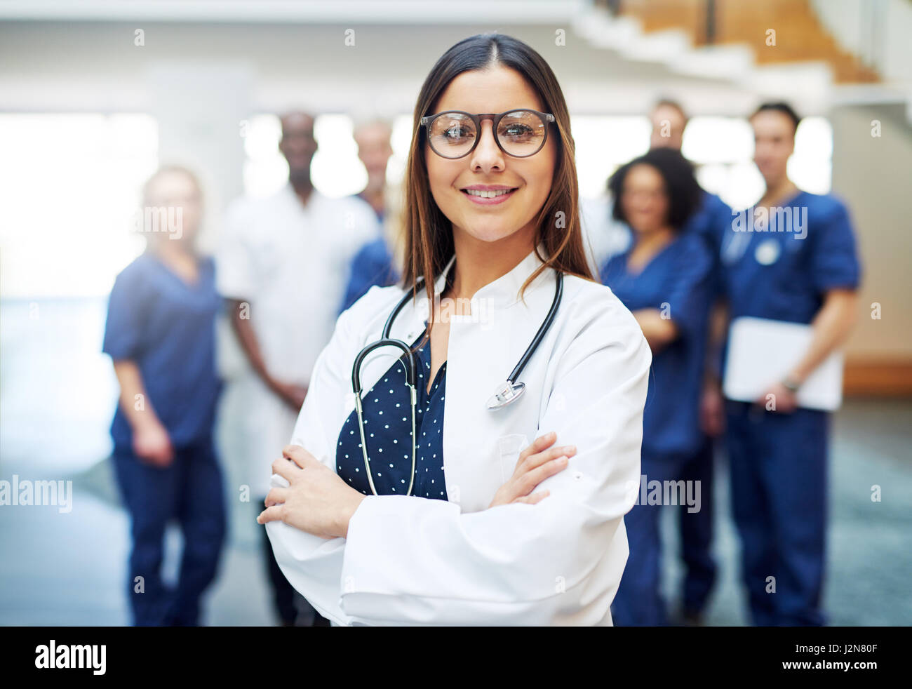 Femme médecin multiraciale, debout devant l'équipe médicale à l'hôpital. Looking at camera and smiling Banque D'Images