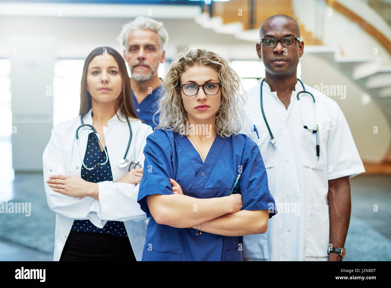 Un certain groupe de médecins avec les bras croisés debout dans un hôpital et à la recherche à l'appareil photo. Banque D'Images