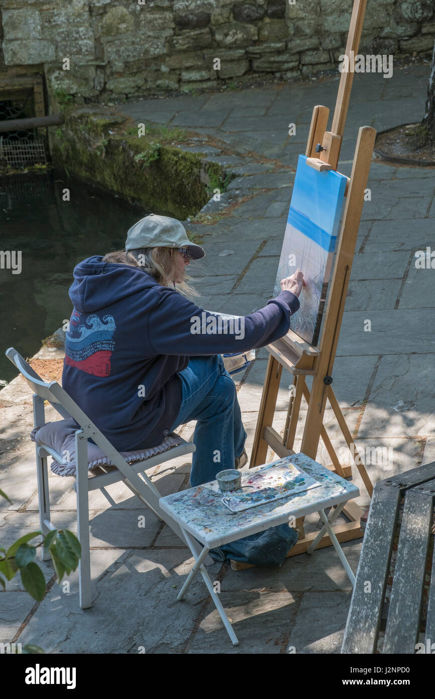Artiste au travail à l'extérieur, la peinture d'une séance photo avec la toile sur un chevalet, près de la Place Moulin, Christchurch Quay, Dorset, England, UK. Banque D'Images