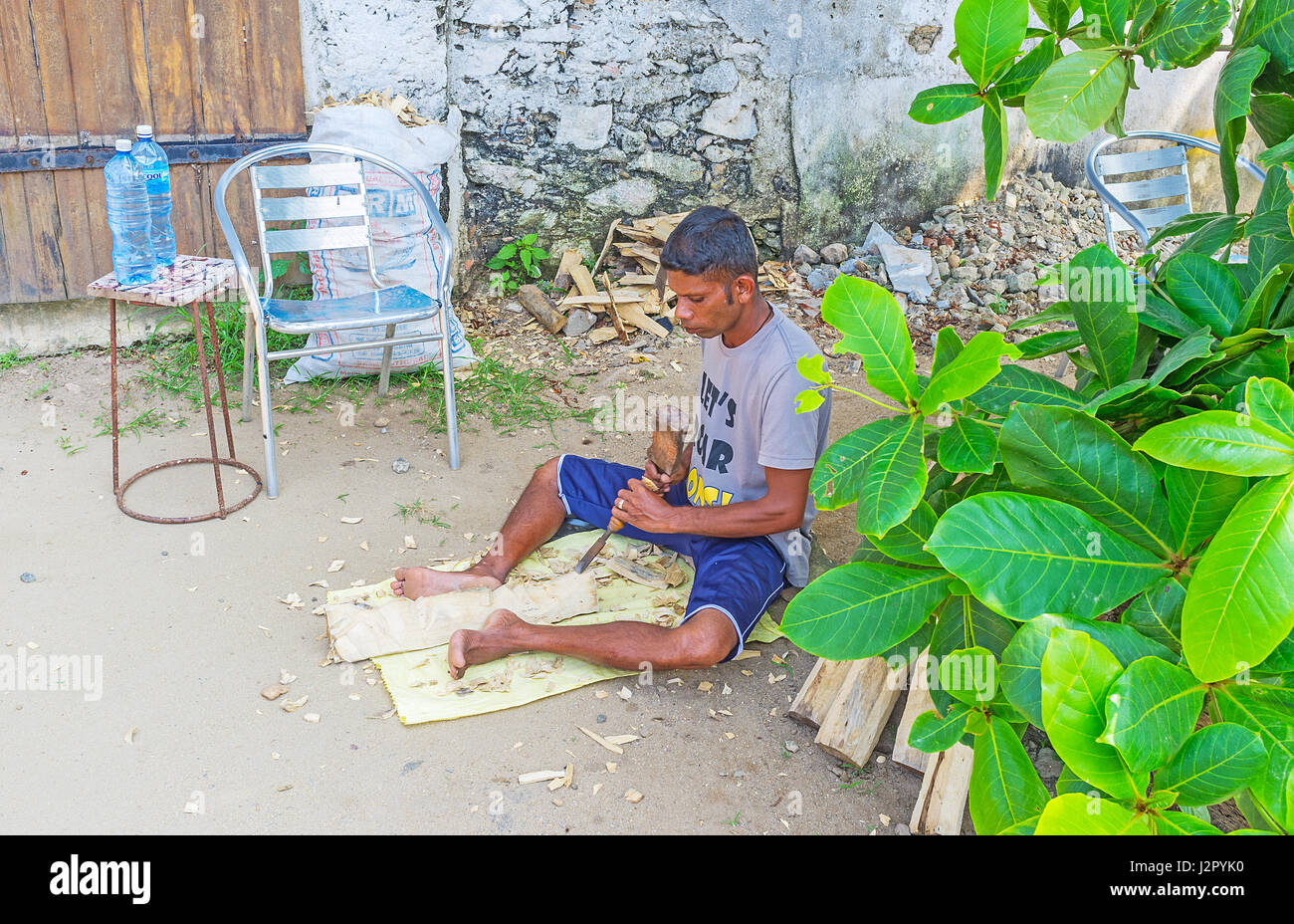 GALLE, SRI LANKA - 4 décembre, 2016 : Le jeune artisan produire le masque en bois dans la cour de son atelier, le 4 décembre à Galle. Banque D'Images