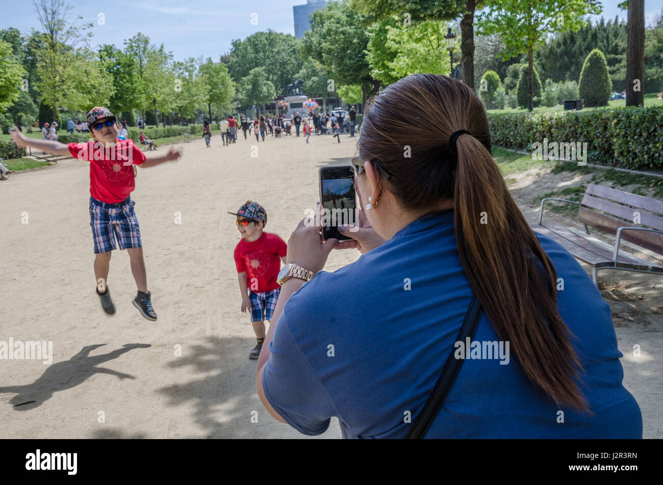 Une maman prend une photo de ses fils avec l'iPhone il faire star sauts dans le Passeig de Lluís Companys à Barcelone. Banque D'Images