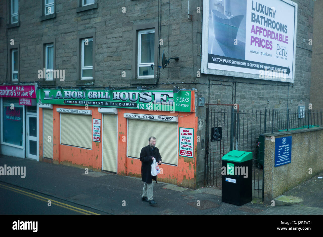 L'homme passe devant un magasin fermé à Forfar rodad un quartier délabré de Dundee en Écosse Banque D'Images