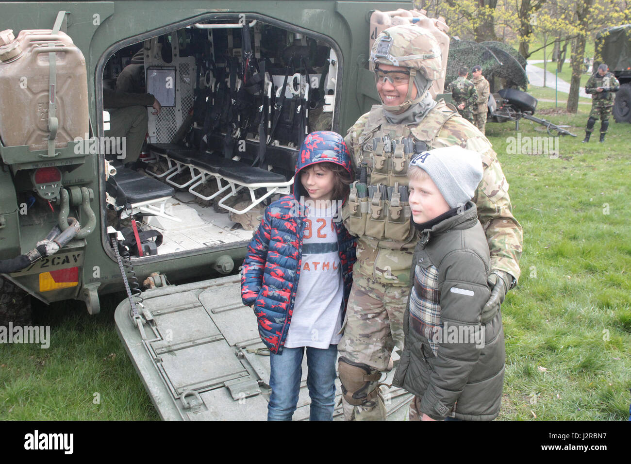 Un groupe de combat Pologne soldat américain pose avec les enfants, sur la rampe d'un Stryker lors d'une exposition statique à une académie militaire à Elk, Pologne, le 22 avril. Des familles sont venues par pour voir l'équipement de l'OTAN et rencontrer les soldats en personne. La formation unique composé de États-Unis, Royaume-Uni, en roumain et en soldats polonais, servira de force de dissuasion dans le nord-est de la Pologne à l'appui de l'OTAN vers l'amélioration de la présence. (U.S. Photo de l'armée par la FPC. Brandon Shiplett/libérés) Banque D'Images