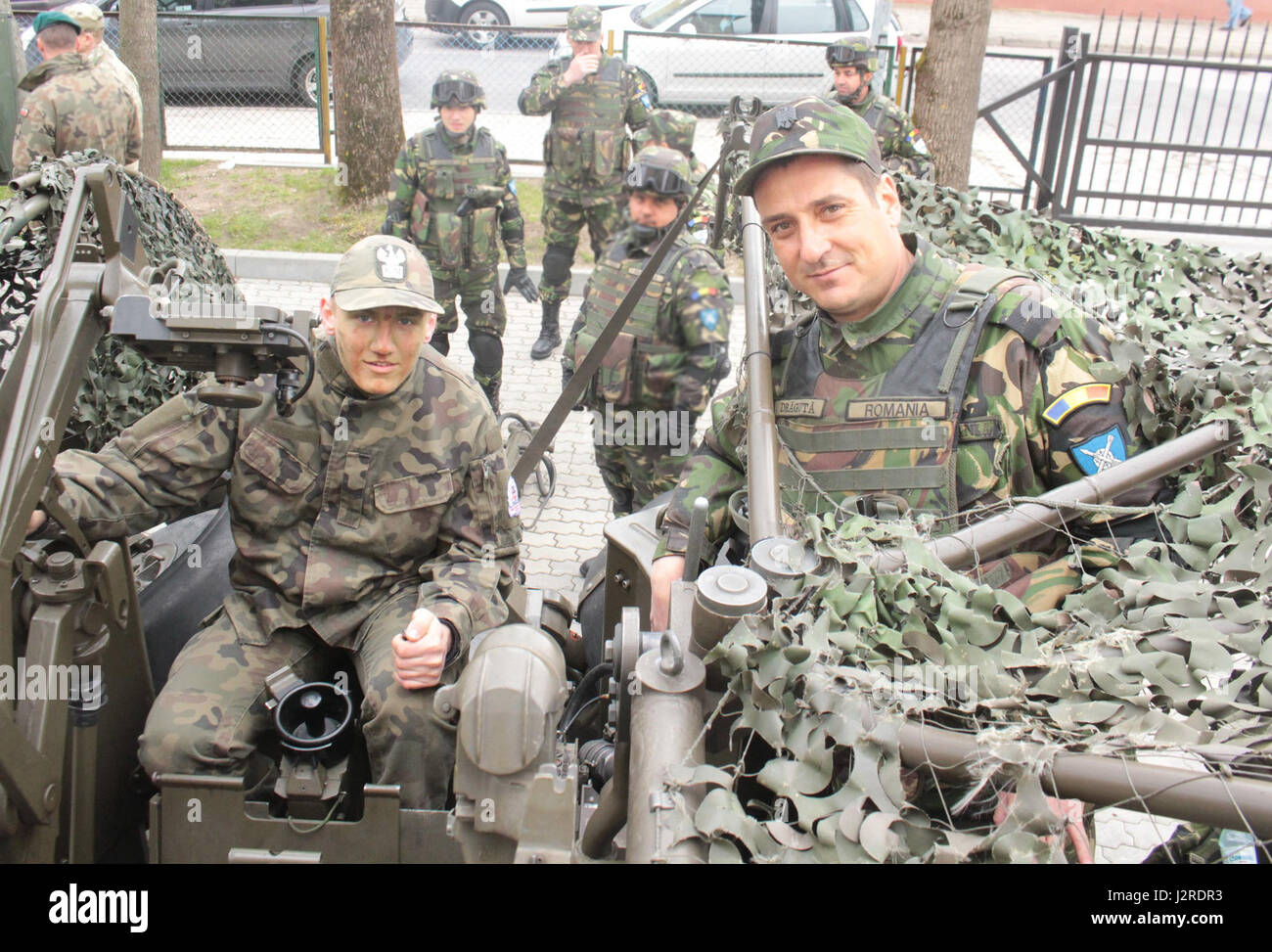 Un élève du secondaire pose sur un canon avec un groupe de combat de la Roumanie Pologne soldat à Stol DOSKONALENIA ZAWODOWEGO, une école militaire, à Gizycko, Pologne 25 avril. Le groupe tactique a participé à une exposition statique pour les élèves du secondaire de l'école au cours de la journée portes ouvertes permettant aux élèves et les citoyens polonais d'interagir avec l'unité multinationale et explorer son équipement de combat. L'unique formation d'américains, britanniques et soldats roumains sont en service avec Polish 15e Brigade mécanisée de soldats comme une force de dissuasion dans le nord-est de la Pologne à l'appui de l'amélioration de l'OTAN Banque D'Images