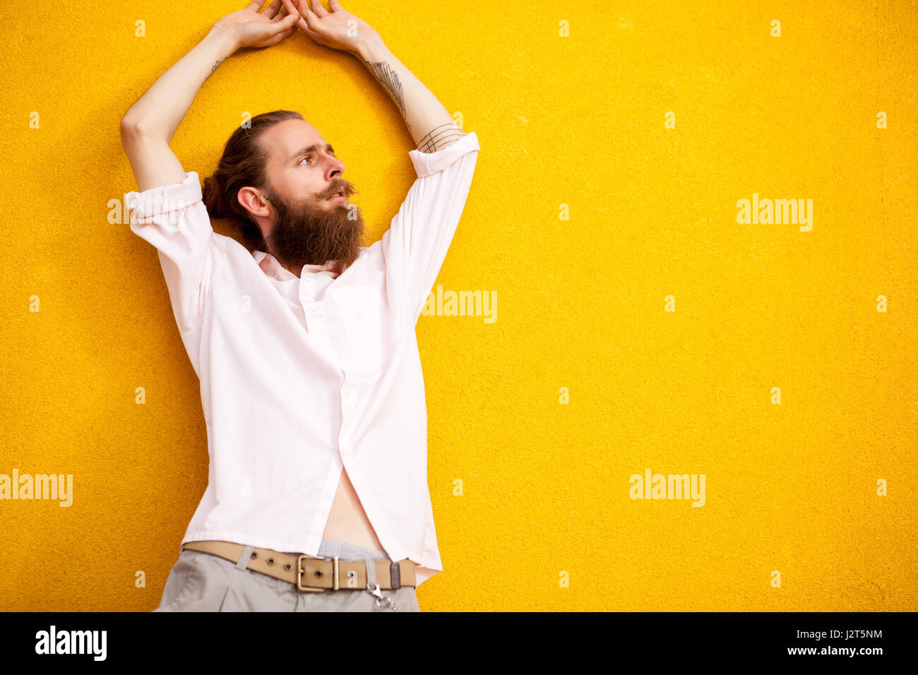 Homme barbu tatoué sur mur jaune Banque D'Images