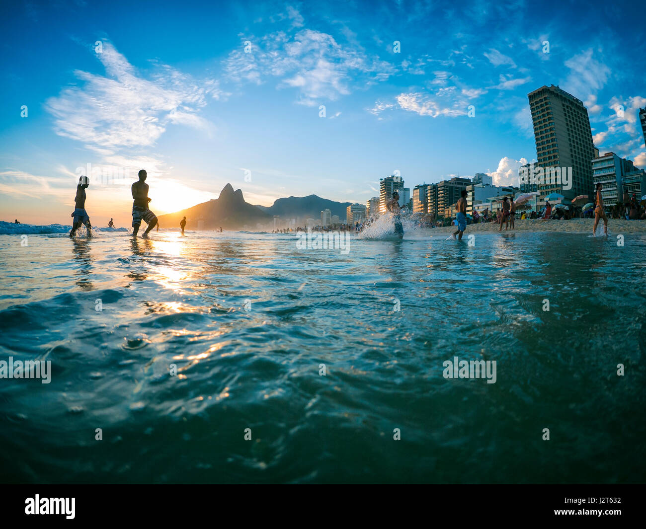 RIO DE JANEIRO - le 2 février 2013 : Silhouettes passent devant le coucher du soleil sur la rive de la plage d'Ipanema. Banque D'Images