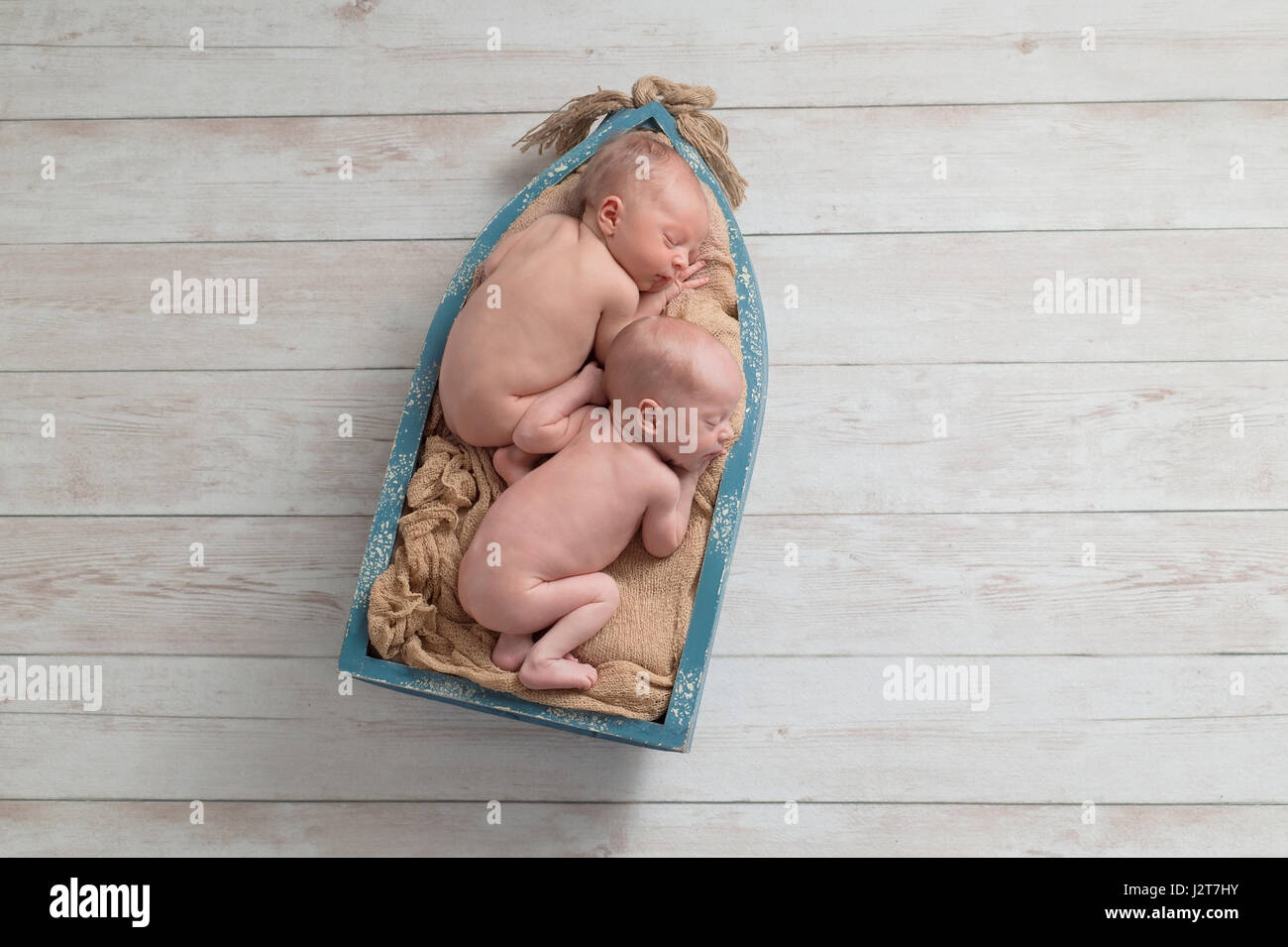 Six jours, fraternelle, lits jumeaux nouveau-né, bébé garçon dormir dans un minuscule bateau en bois. Tourné en studio sur un fond de bois. Banque D'Images