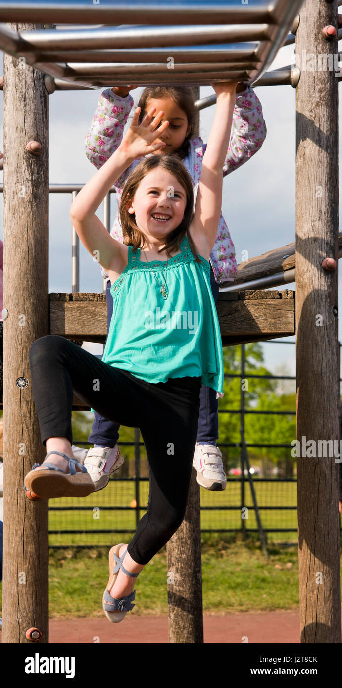 Portrait vertical d'une jeune fille se balançant le long de barres à une aire de jeux. Banque D'Images