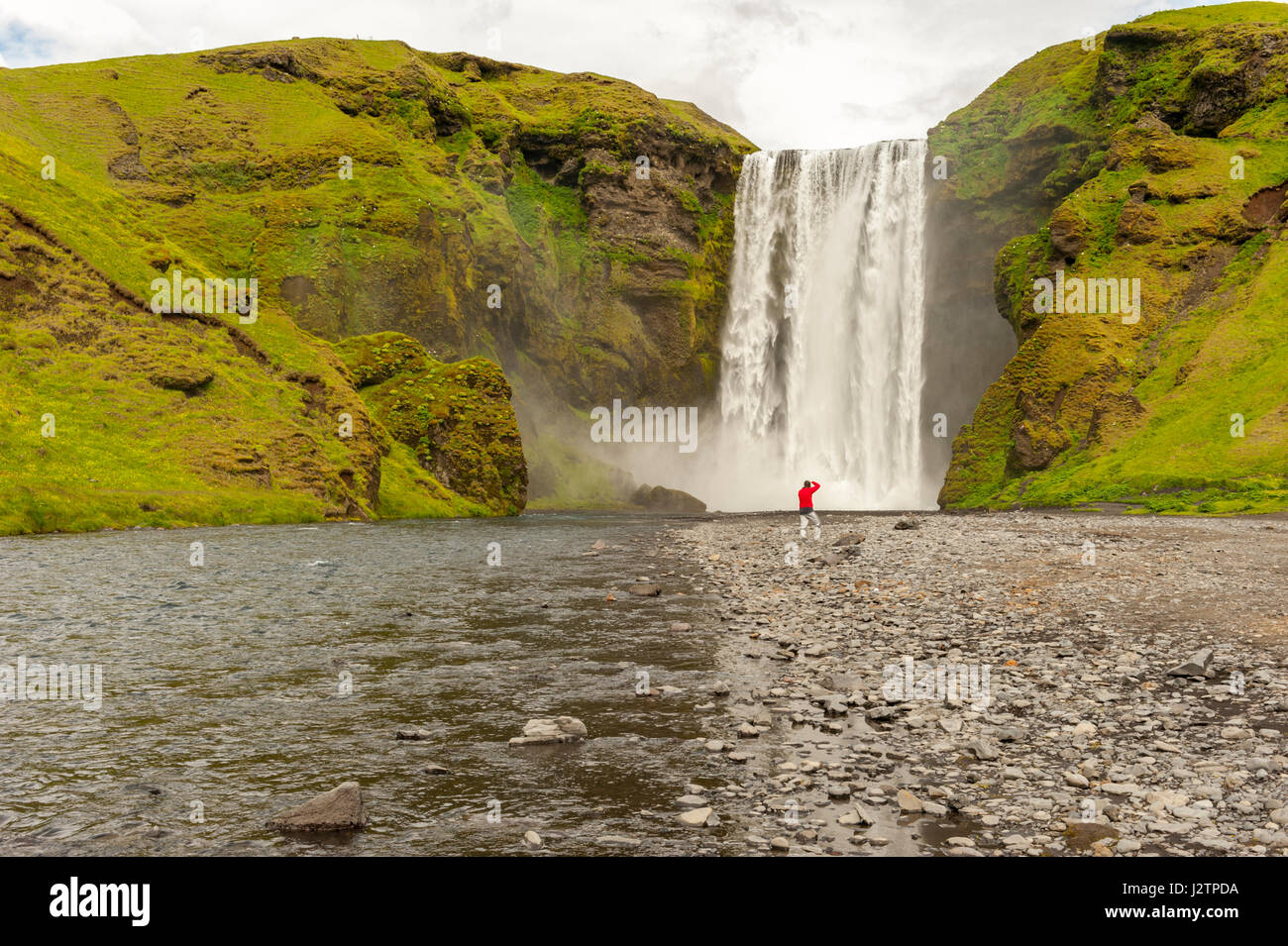 Photographe mâle au bas de cascade de Skogafoss, de photographier, de brume, de cascades d'Islande. Banque D'Images
