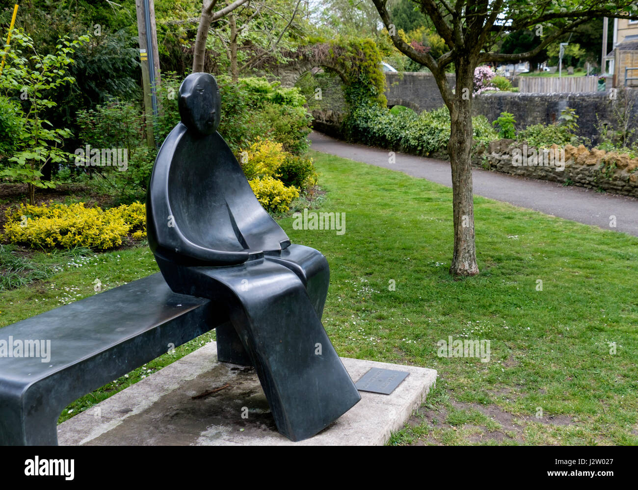 L'homme sur un banc de la statue par Giles Penny à Bruton, une petite ville de Somerset England UK Banque D'Images