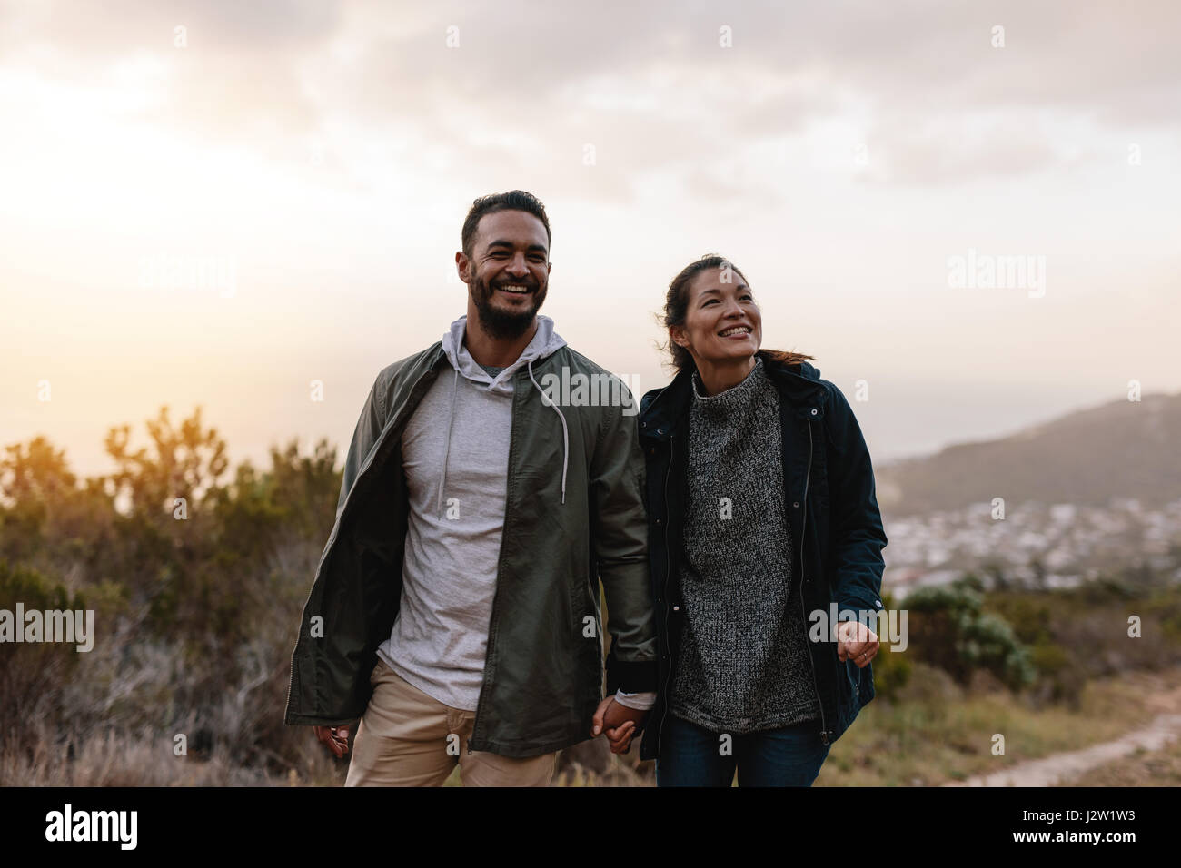 Portrait de couple d'heureux Randonneurs marchant dans la campagne. Jeune homme et femme de la randonnée et à la voiture. Banque D'Images
