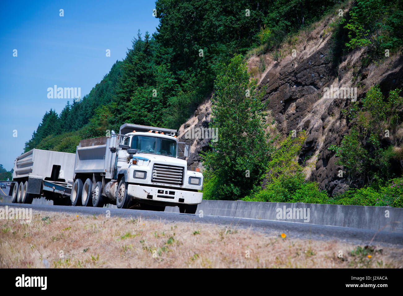 Modèles de camions semi ancienne rétro des années précédentes que le vieux cheval fiables continue de fonctionner aujourd'hui et le transport des marchandises sur une route rocky vert Banque D'Images