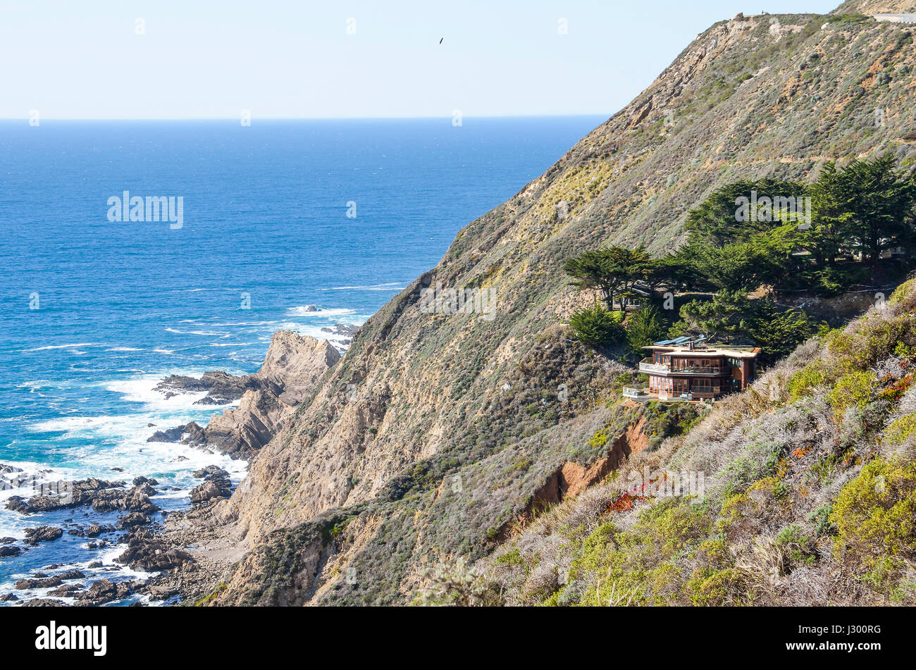Big Sur, USA - 11 mars 2014 : le centre de la Californie Côte avec des falaises et l'océan bleu avec maison sur la falaise Banque D'Images