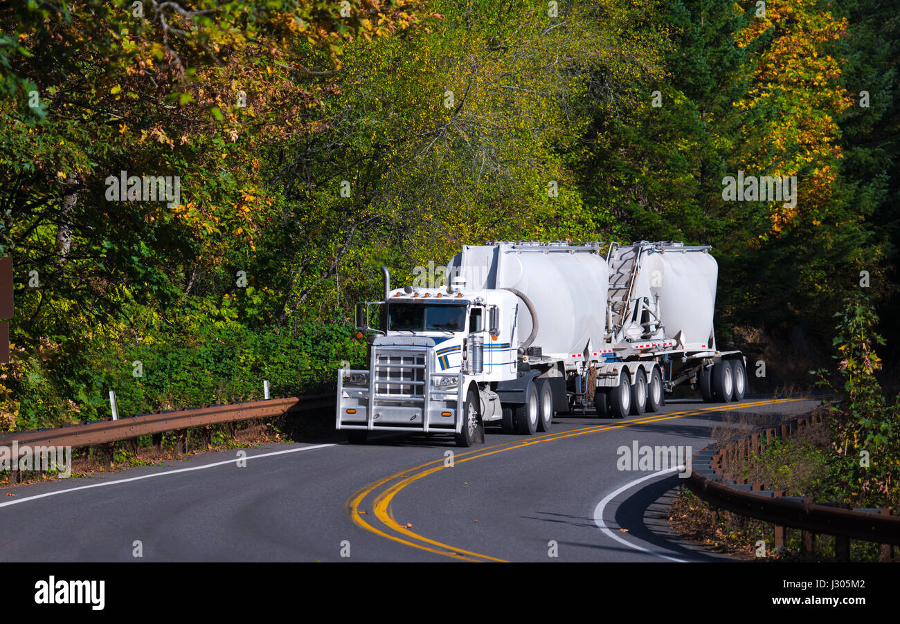 Grand camion semi-remorque professionnel élégant et contrasté avec grille de protection et deux remorques pour les déplacements de chargement en vrac le long de la voie sinueuse Banque D'Images