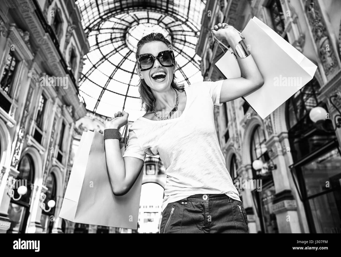 Découvrez les tendances les plus inattendus à Milan. Portrait of smiling fashion femme en lunettes avec des sacs colorés dans la galerie Vittorio Emanuele II Banque D'Images