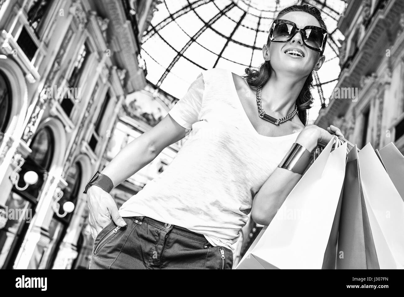 Découvrez les tendances les plus inattendus à Milan. Portrait of happy fashion monger à lunettes avec des sacs colorés dans la galerie Vittorio Emanuele II Banque D'Images