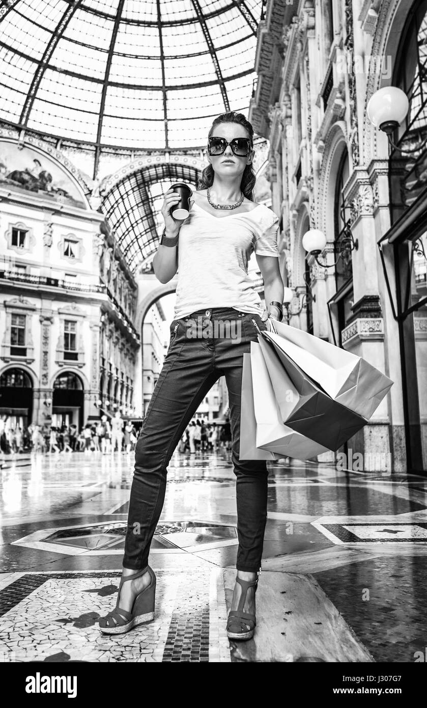 Découvrez les tendances les plus inattendus à Milan. Portrait de la mode monger à lunettes avec des sacs colorés et Coffee cup in Galleria Banque D'Images