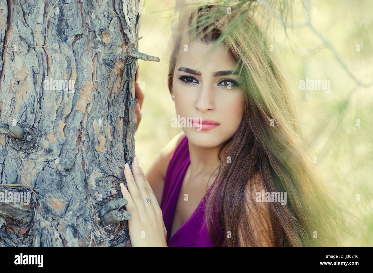 Belle jeune femme appuyée contre un arbre à l'écart Banque D'Images