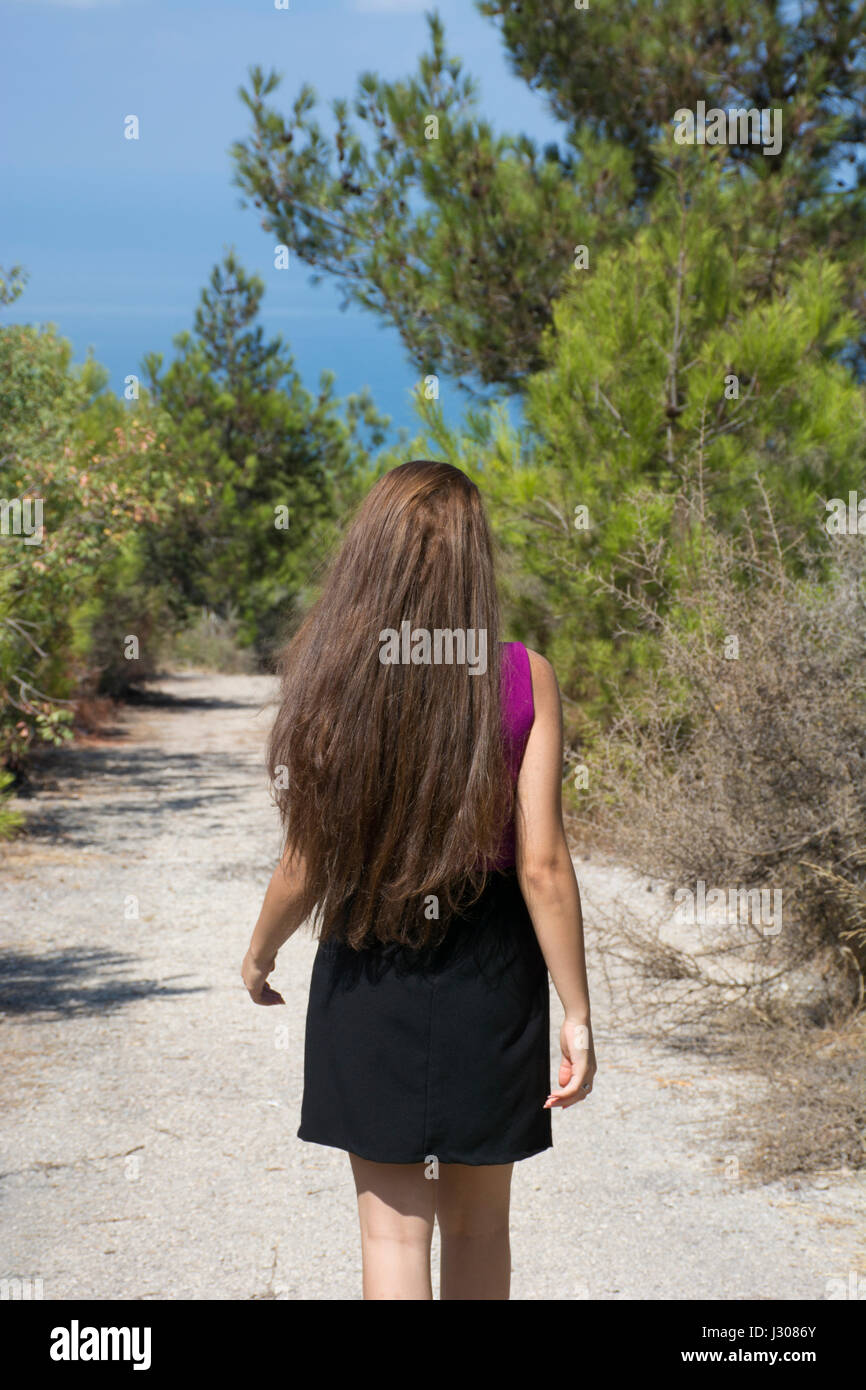 Vue arrière d'une jeune femme aux longs cheveux noirs s'éloigner Banque D'Images