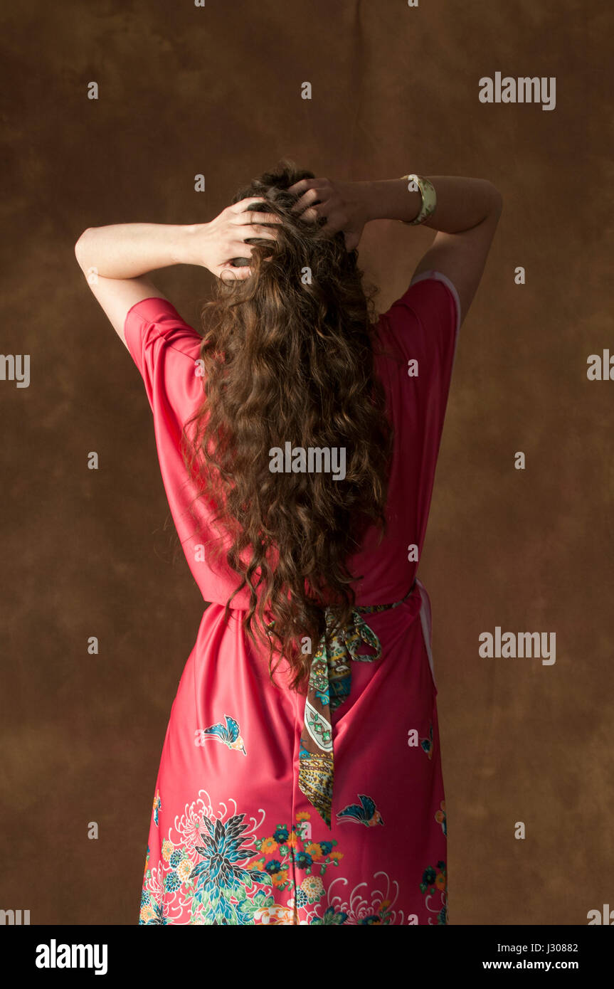 Vue arrière d'une jeune femme portant l'accent sur une robe rouge vintage head in hands Banque D'Images