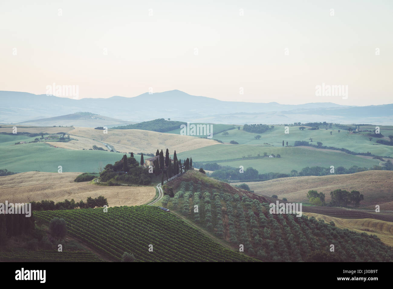 La vue classique du paysage pittoresque de la Toscane avec célèbre ferme au milieu de collines et de vallées idylliques dans la belle lumière du matin au lever du soleil d'or i Banque D'Images