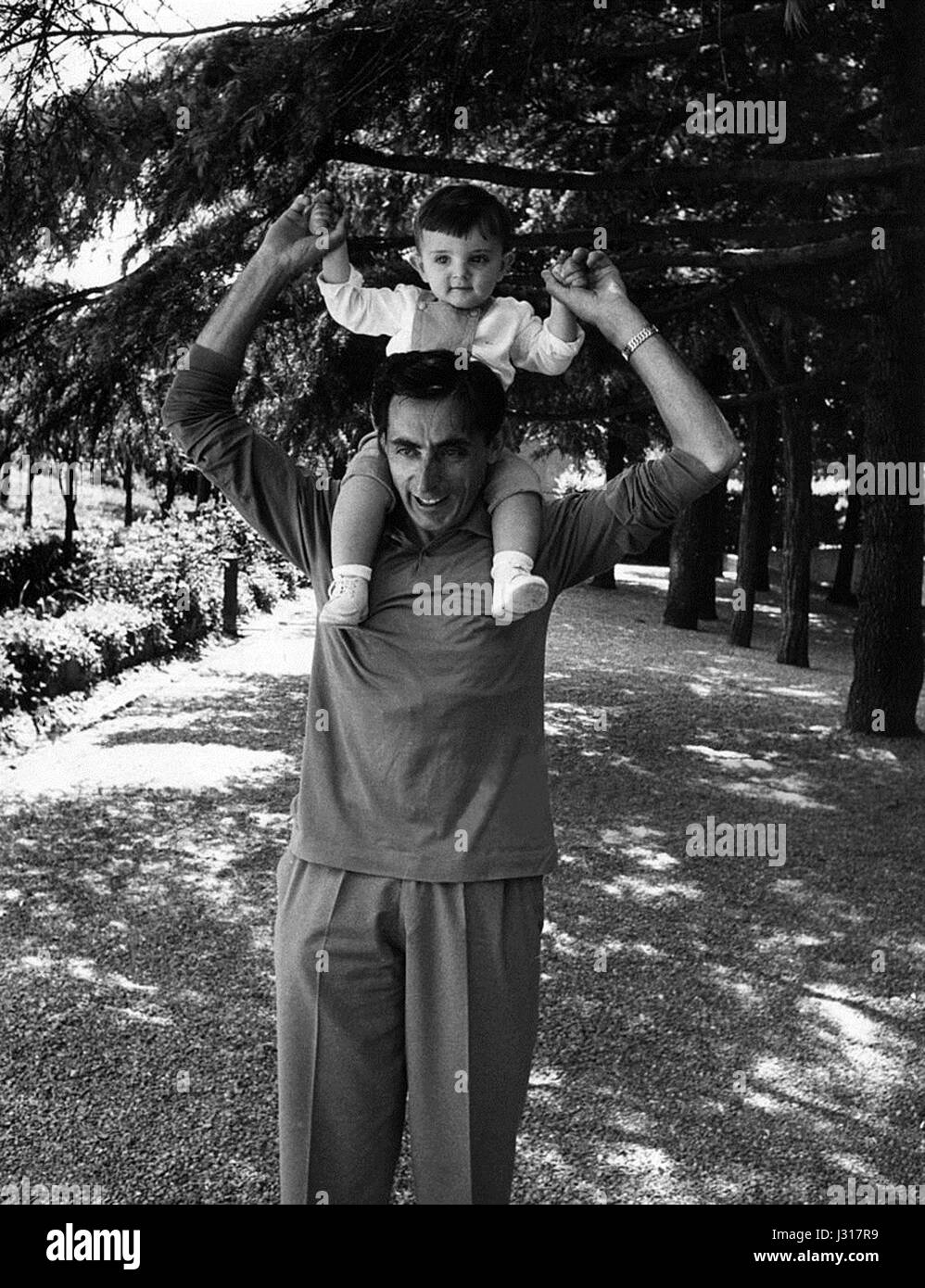 Fausto Coppi, légende italienne du cyclisme, est photographié avec son fils en 1956, capturant un moment personnel du célèbre cycliste connu pour ses réalisations sur le Tour de France et le Giro d'Italia. Banque D'Images